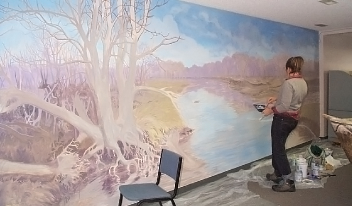 Malena Handeen painting the exhibit mural